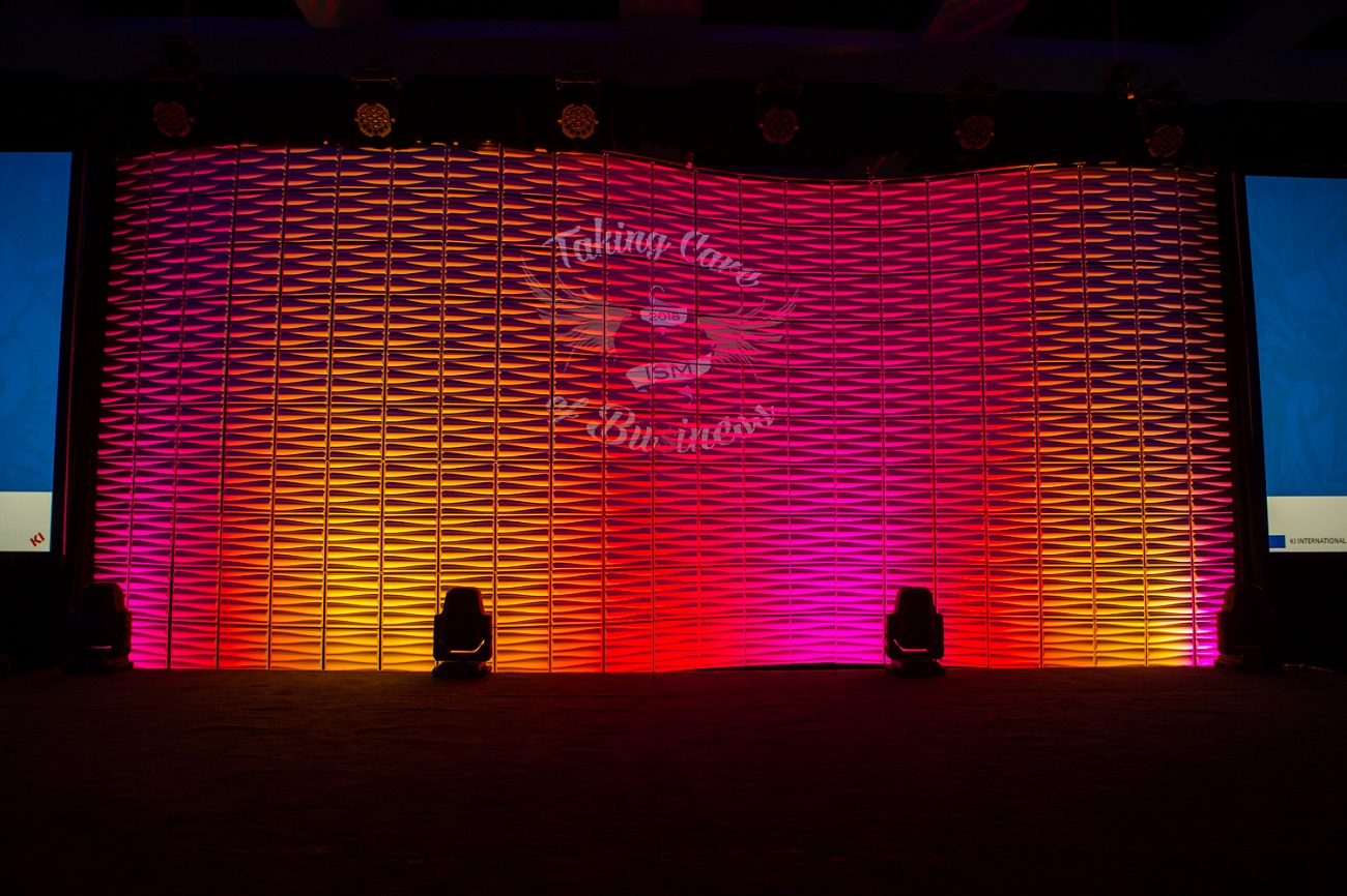 A curved wall of set tiles were centered on stage and lit using LED lights. The tiles are white 18"x18" and can be configured in many ways.